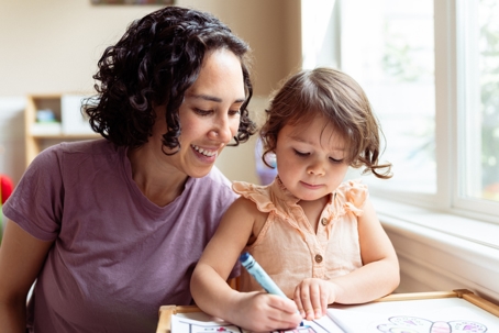mother helping child with coloring book