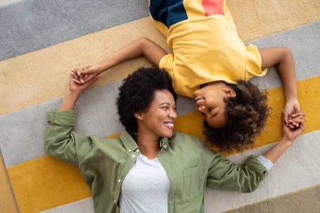 mother and child lying on the floor holding hands