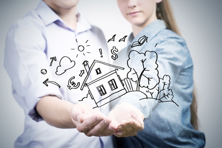 A man and woman holding a graphic of a house