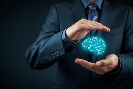 A man in a suite holding a graph of a brain