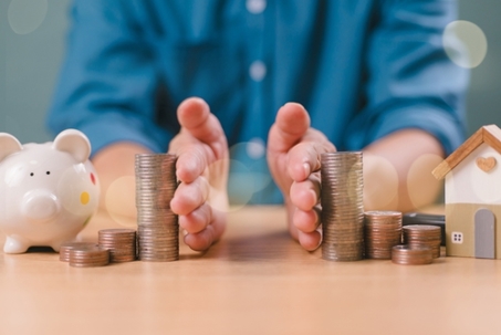 Divorce law and heritage separation concept. Hand separate saving money, financial, home loan, debt with piggy bank and wood house. Bank business investment. Man separate stack coin on table