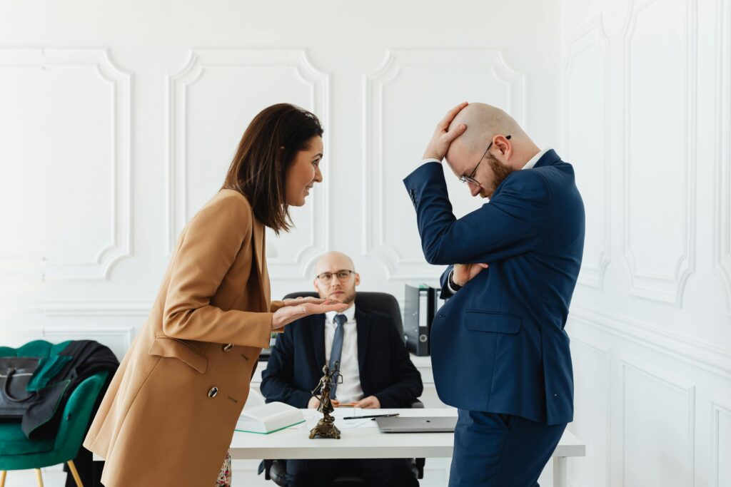 Couple arguing in front of a lawyer during a meeting, illustrating the conflict and legal disputes involved in a contested divorce.