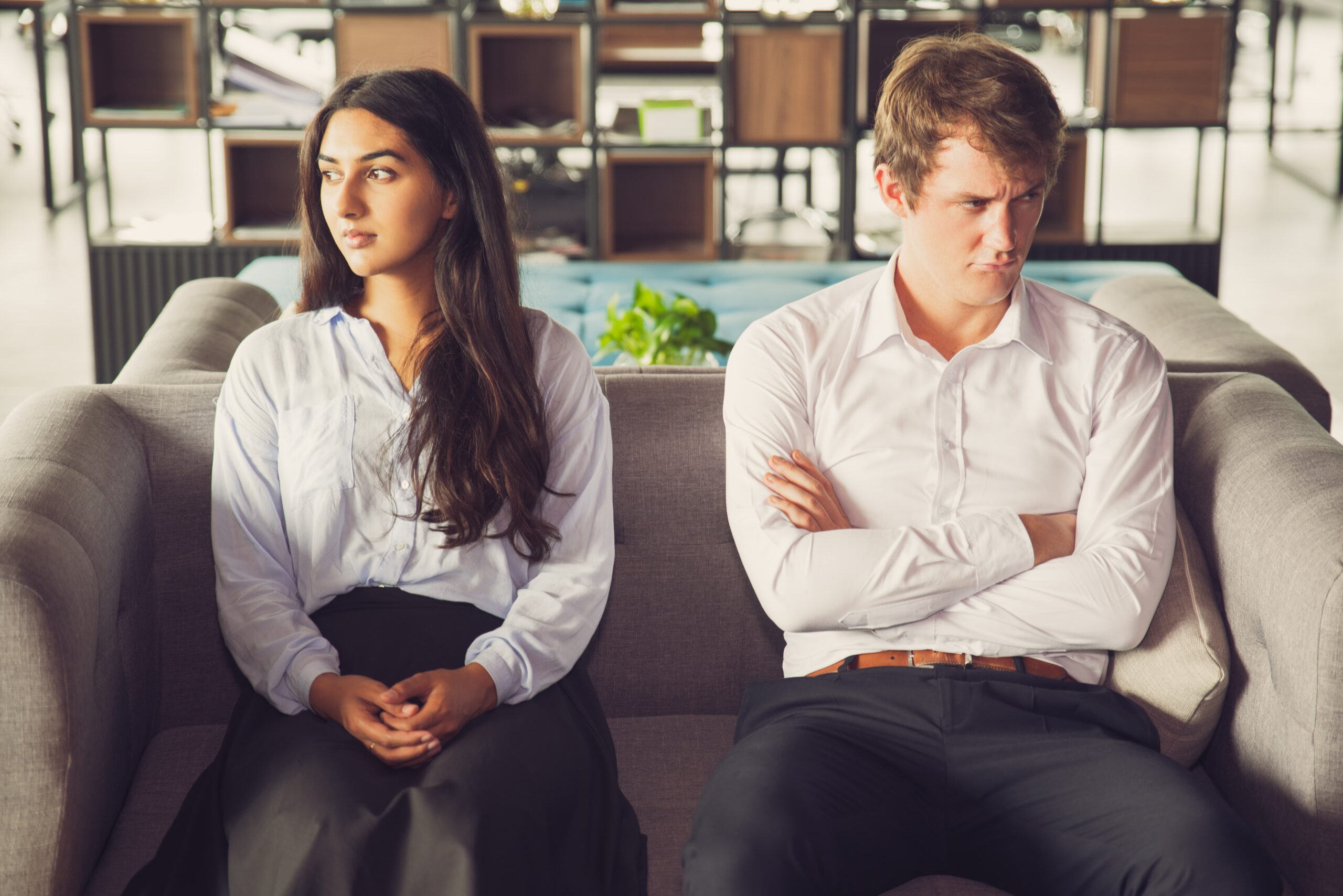 A couple sitting in silence and avoiding eye contact, representing the emotional tension and different legal paths of contested versus uncontested divorce in Colorado.
